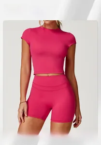 Front view of rose pink high-neck crop top and high-waist yoga shorts on athletic model