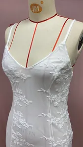 Detailed view of floral lace embroidery and mesh fabric on a white evening dress