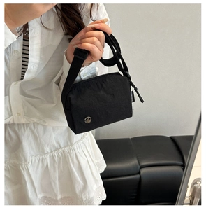 Dettaglio macro della borsa a tracolla in nylon nero con tessuto e logo M in metallo