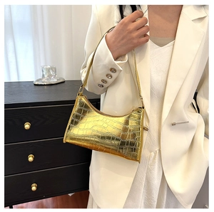 Metallic gold crocodile pattern shoulder bag shown on model in a stylish lifestyle setting