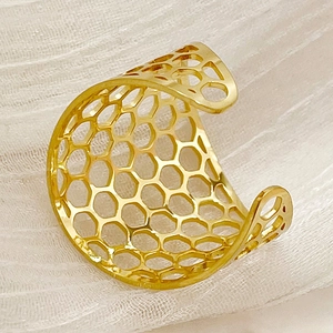 Minimalist gold honeycomb open ring with hollow grid design on white textured background