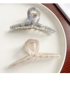 Detail of blue and pink acetate hair claws with sparkling rhinestones on a white plate