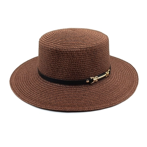 Détail de la texture d'un chapeau de paille marron avec sangle en cuir et boucle dorée