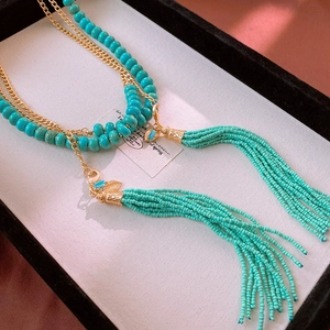 Detail view of Bohemian multi-layer turquoise bead necklace with golden fringe tassels