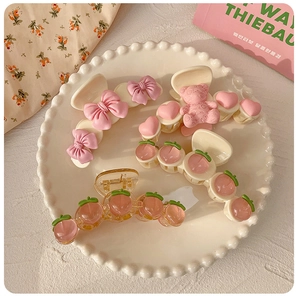Detail of sweet peach hair claws and bear bows set on a white ceramic plate