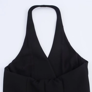 Detail of black halter neck mini dress featuring a deep V-neckline and smooth fabric texture