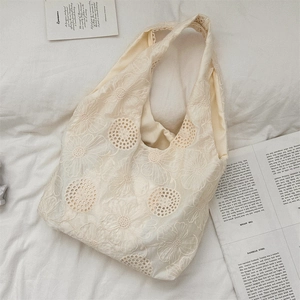 Close-up of intricate hollow crochet flower patterns on the cream white lace tote bag