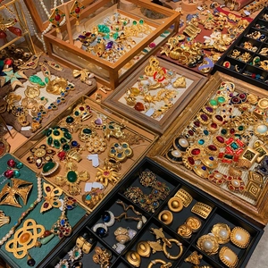 Collezione di gioielli vintage dorati con pietre colorate e perle su vassoi
