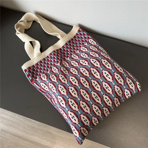 Detail of large knit tote bag with red, blue, and white geometric diamond woven patterns