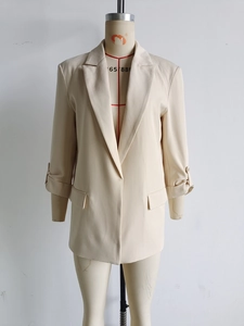 Detail of rolled cuffs with buttons on a beige women's minimalist casual blazer