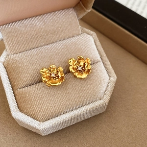 Macro view of 24K gold plated flower earrings with zircon in a beige velvet box