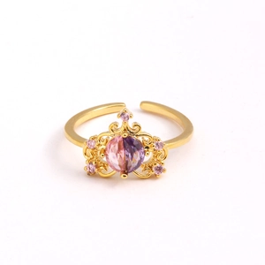 Gros plan d'une bague couronne dorée avec strass roses et violets sur fond blanc