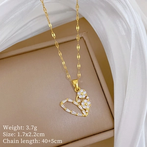 Macro detail of a gold heart necklace pendant with floral pattern and tiny crystals