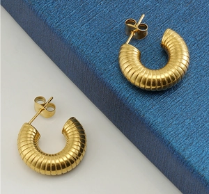 Macro detail of gold-plated U-shaped earrings with textured spiral grooves