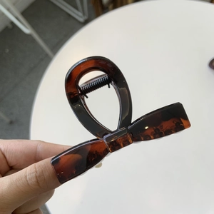 Macro detail of tortoiseshell pattern hair claw clip with butterfly bow design