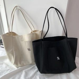 Detail of minimalist canvas tote bag featuring front pocket and printed logo design