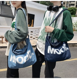 Outdoor shot of denim crossbody bags in light and dark blue with MOOD lettering
