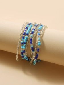 Detail of layered bohemian waist beads wrapped on a beige prop in blue and clear tones