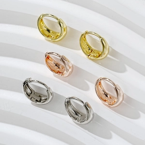 Three pairs of hoop earrings in gold, silver and rose gold on a stone plate