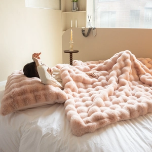 Detail of pink faux fur blanket with a 3D grid texture and soft plush material