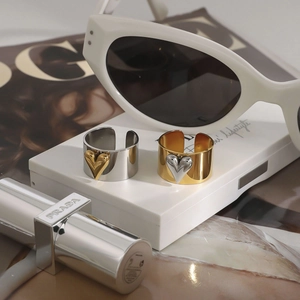 Two-tone heart shaped wide band rings in gold and silver on a white display stand