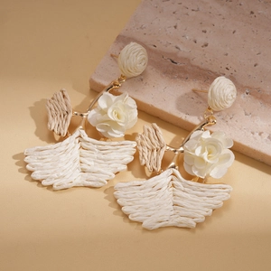 Detailed macro view of bohemian raffia flower earrings on a textured stone display