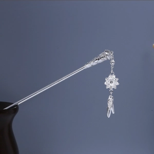 Detailed view of an ornate silver hairpin featuring carved flower and leaf drop pendants