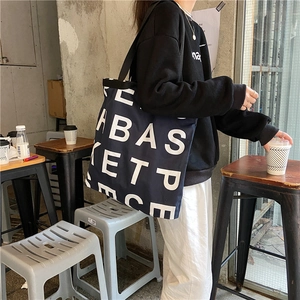 Detail of navy blue canvas tote bag with white letter print in casual lifestyle setting