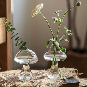 Détail de vases en verre transparent en forme de champignon avec plantes sur lin