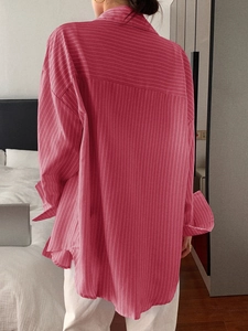 Rear view of a pink striped loose-fitting long sleeve shirt on a professional model