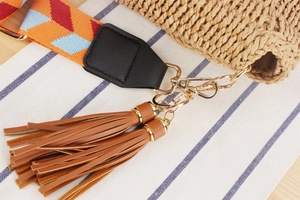 Detail of woven bag strap with colorful geometric patterns and leather tassel charms