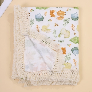 Close-up of muslin baby blanket showing tassels and cartoon animal patterns