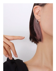 Detail of a hollow heart stud earring with pavé zircon inlays on model's ear