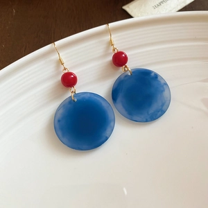 Détail de boucles d'oreilles vintage en acrylique avec motifs nuages bleus et perles rouges