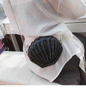 Dettaglio di una borsa a tracolla nera a forma di conchiglia con catena d'oro e perla