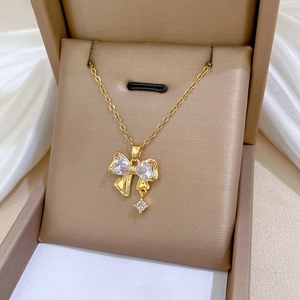 Macro detail of bow-shaped gold necklace pendant set with sparkling zircon stones