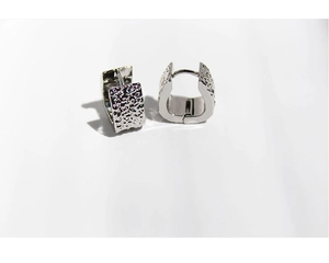 Macro detail of silver geometric earrings with a unique hammered metal texture surface