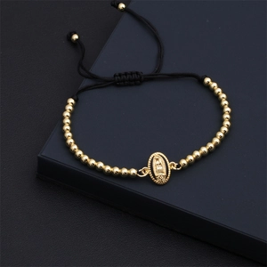 Detail of gold Virgin Mary charm bracelet with black adjustable cord on a gift box