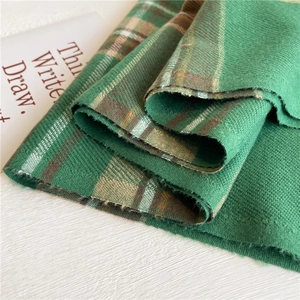 Dettaglio della trama di sciarpa a quadri verde in finto cashmere con bordi a frange