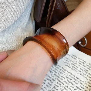 Detail of amber acrylic resin bangle showing translucent gradient texture and glossy finish