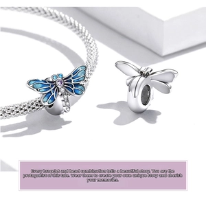 Detail of silver dragonfly charm with blue enamel wings and gemstones on mesh bracelet