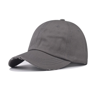 Detail of distressed brim and stitched eyelets on a dark grey washed cotton baseball cap