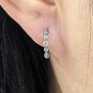 Close-up of S925 silver drop earrings with graduated white zircons on female ear lobe