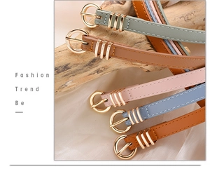 Detail of colorful slim leather belts with gold round buckles and white stitching details