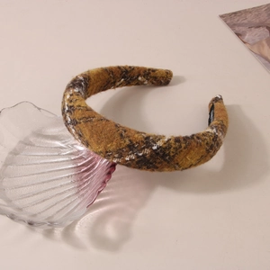 Macro shot of brown and yellow plaid wool headband on a pink shell decorative plate