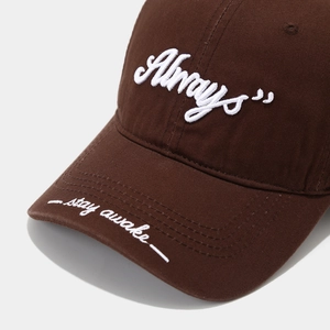 Detail of coffee brown cotton baseball cap with white 'Always stay awake' embroidery