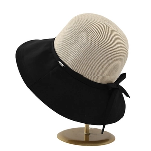 Straw sun hat with black bow and mixed fabric weave on metal display stand