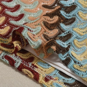 Détail du tissu en dentelle au crochet avec des motifs texturés bleu, orange et marron