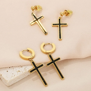 Detailed view of gold cross earrings with black inlay on silk and stone background