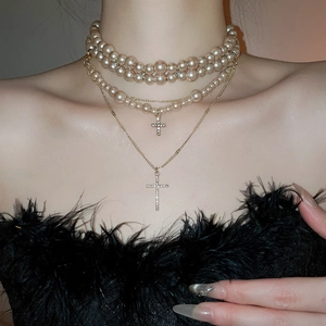 Close-up of layered champagne pearl necklace with sparkling rhinestone cross pendants
